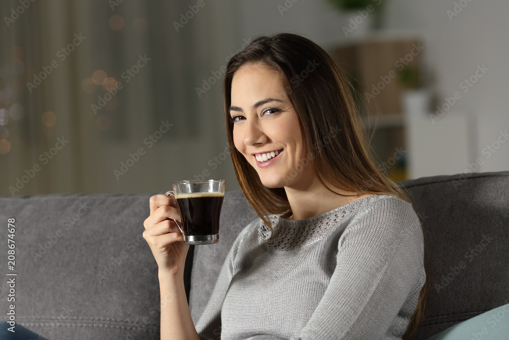 Woman holding coffee cup in the night looking at you Woman holding coffee cup in the night looking at you