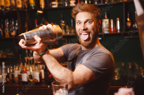 Joyful bartender mixes a cocktail in a shaker