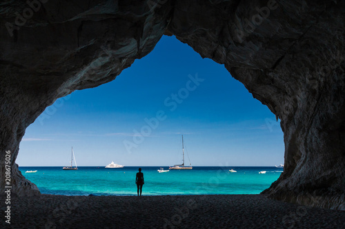Fotografiet Woman inside a cave at Cala Luna beach