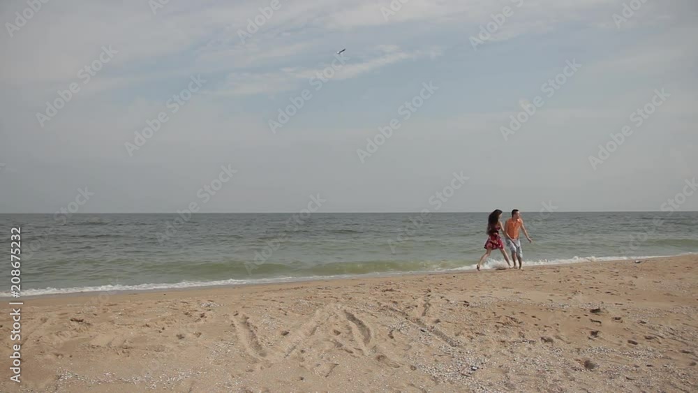a pair of lovers having fun on the sand in the surf line a pair of lovers having fun on the sand in the surf line