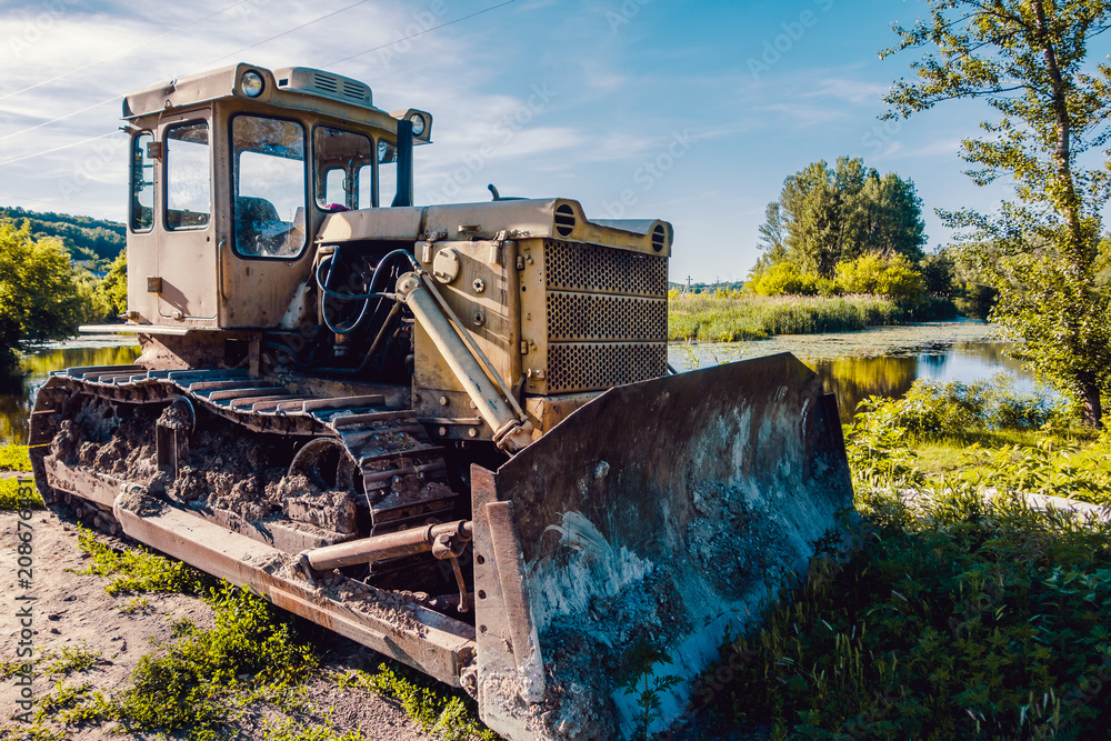 Fototapeta premium bulldozer in the summer light on the nature grass field