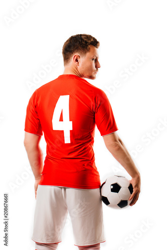 Young soccer player with ball on black background in studio.