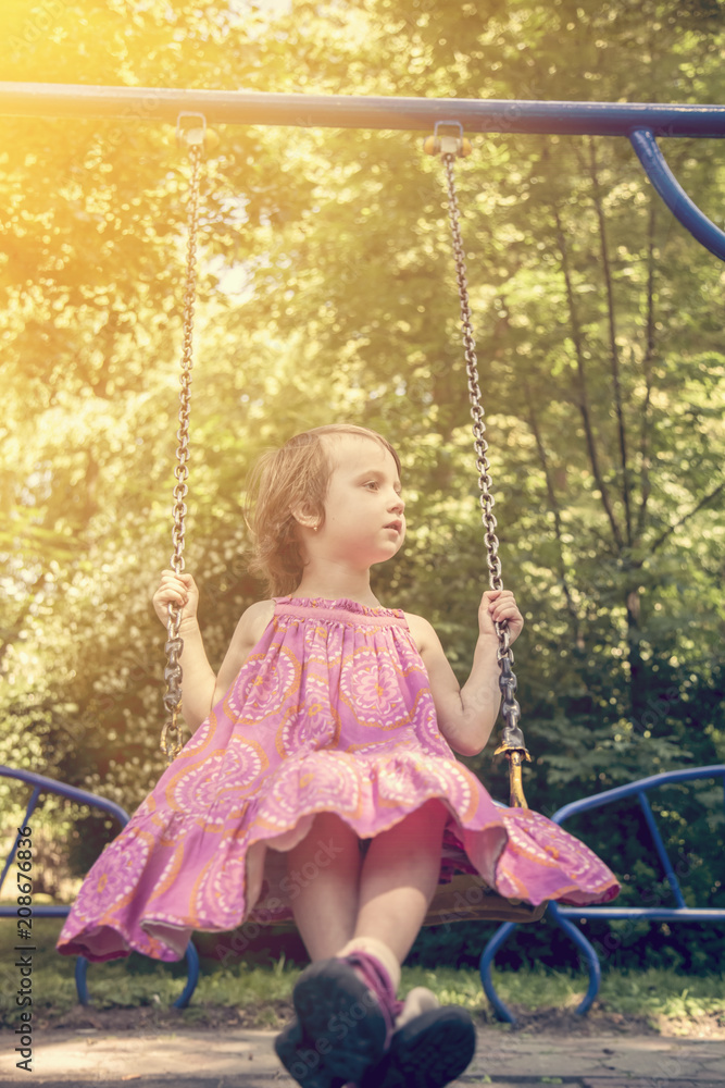 Cute little child girl having fun on a swing on a playground outdoors. Happy childhood and summer outdoor leisure for kids concept. Cute little child girl having fun on a swing on a playground outdoors. Happy childhood and summer outdoor leisure for kids concept.