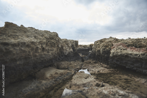 Unique canyon in rock cliff. Clear water in natural pool inside. Cloudy sky on background 