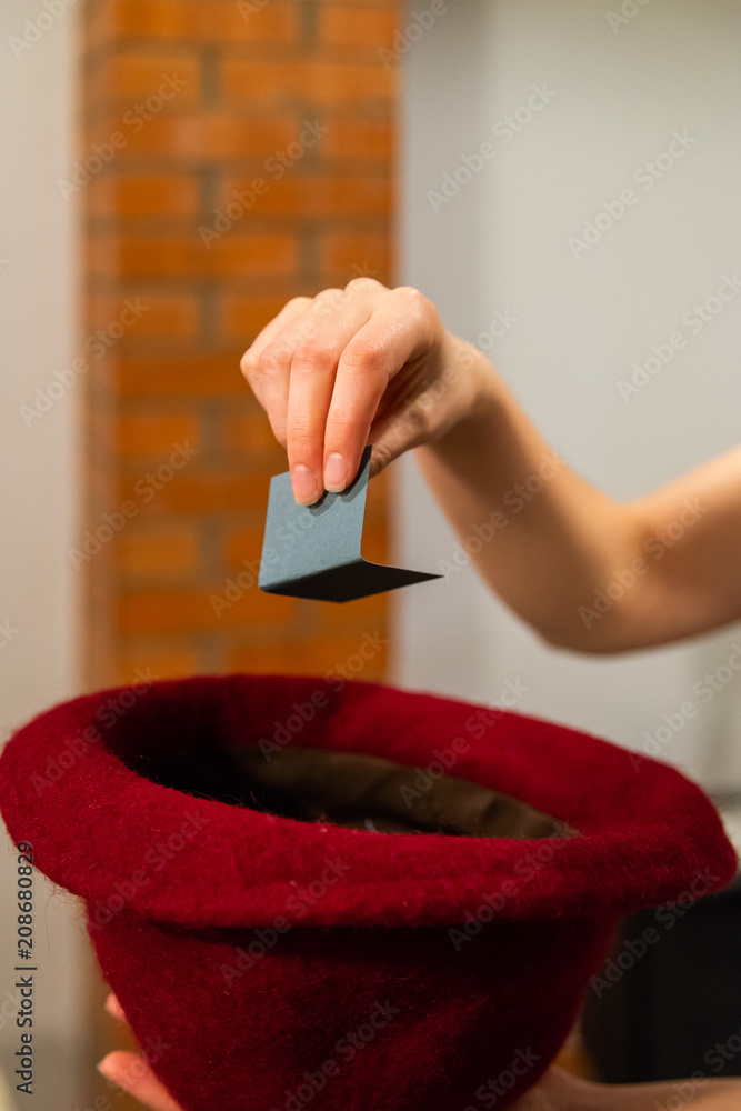 Woman hand take a card with a name from hat