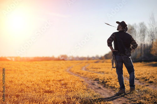 A man cowboy hat and a loso in the field. American farmer in a f © alexkich