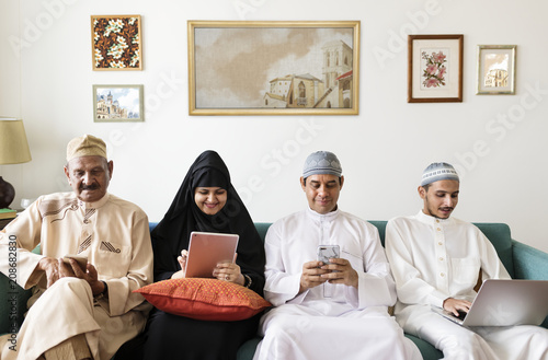 Muslim family using digital devices at home photo