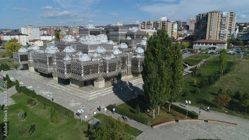Low angle drone flight past iconic National Library of Kosovo building, revealing abandoned Serbian Orthodox church in Pristina, education and architecture Kosovo Europe Low angle drone flight past iconic National Library of Kosovo building, revealing abandoned Serbian Orthodox church in Pristina, education and architecture Kosovo Europe