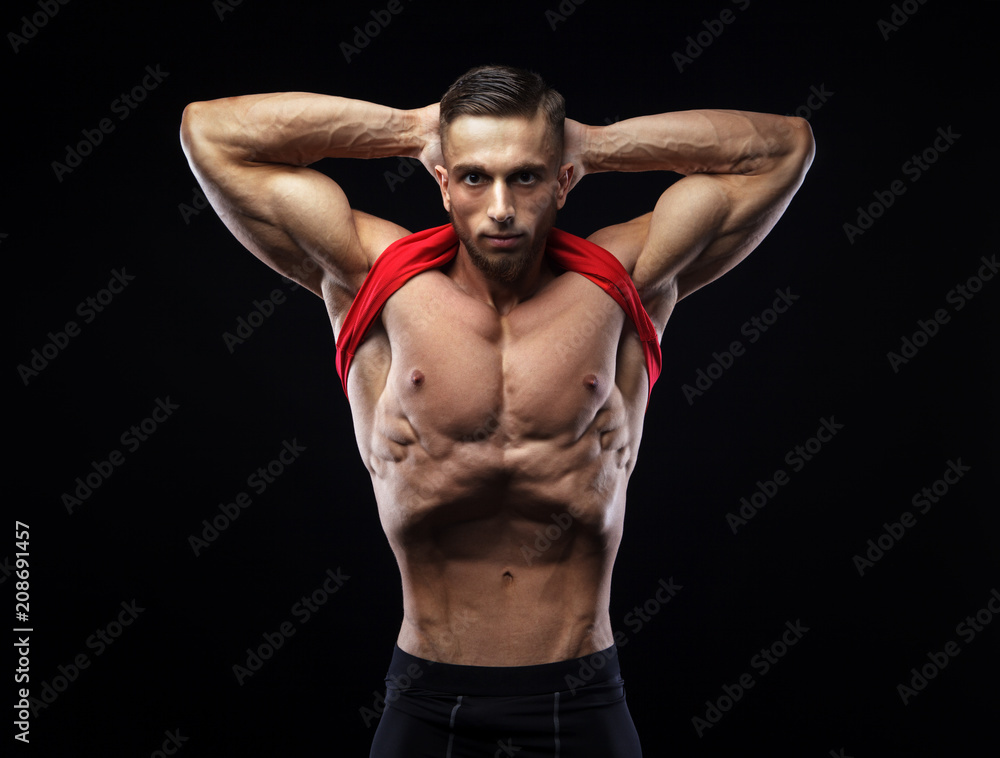Cute young sports man in red t-shirt shows relief and vacuum abdominal muscles