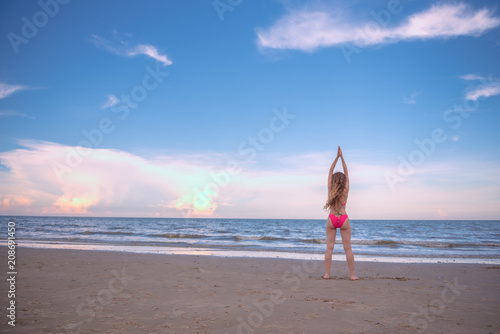 Young healthy woman with blonde curly hair doing yoga on the beach, heathy and relaxing concept.
