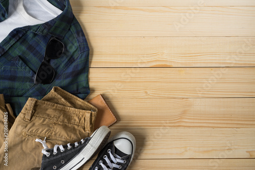 Casual outfit and accessories, Top view of flannel plaid shirt , chino pants and casvas sneakers on wooden backgroud with copy space