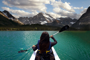 Person kayaking in beautiful blue lake with mountain scenery, peaceful travel adventure 