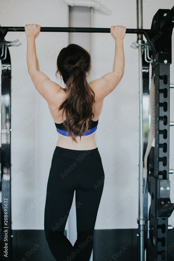 attractive young woman working out doing pullups attractive young woman working out doing pullups