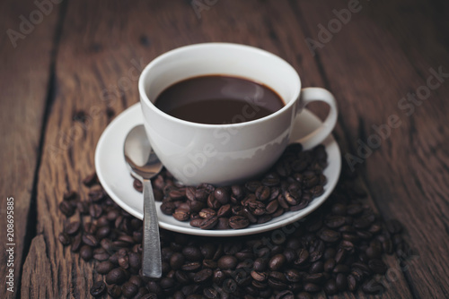 Fototapeta Naklejka Na Ścianę i Meble -  Coffee cup with coffee beans on wood table.