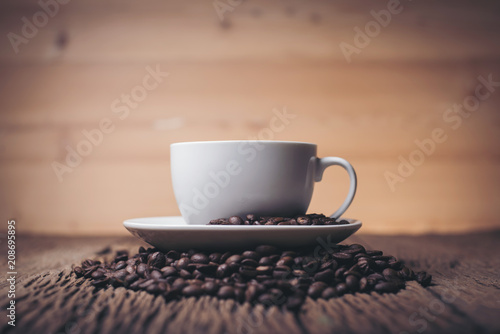 Coffee cup with coffee beans on wood table.