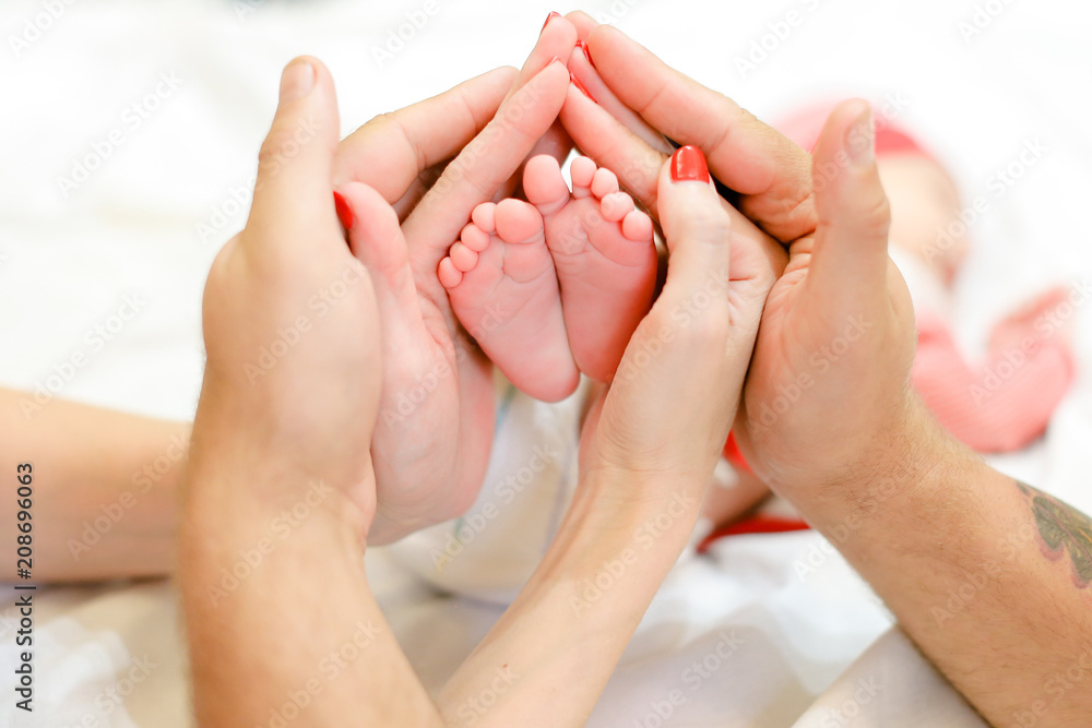 Parents hands holding newborn baby legs. Concept of happy family and babes. - obrazy, fototapety, plakaty 