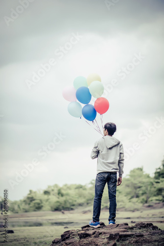 Young man hand holding colorful balloons