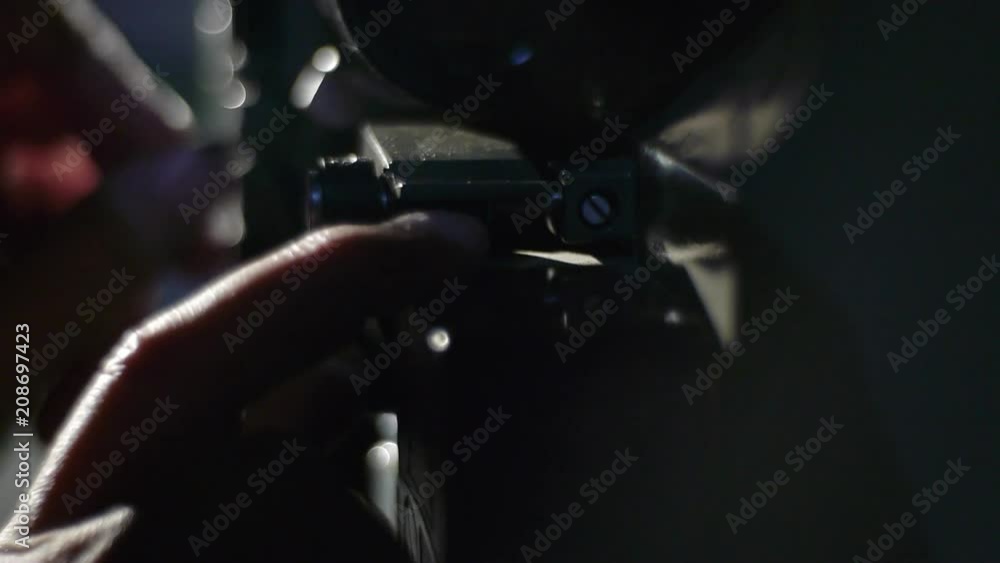 The old film projector plays in a dark room. A projectionist, close-up of a hand loading a film into a film projector The old film projector plays in a dark room. A projectionist, close-up of a hand loading a film into a film projector