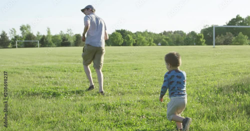 Toddler running after father on soccer field - slow motion during sunset Toddler running after father on soccer field - slow motion during sunset