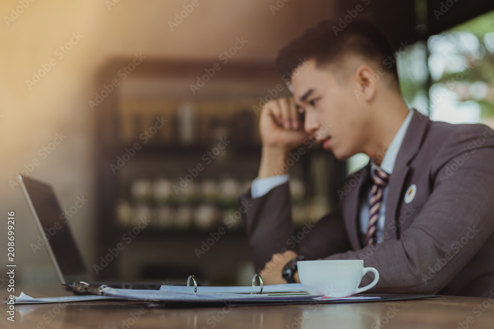 Portrait of young man sitting at his desk in the cafe. Businessmen stress.