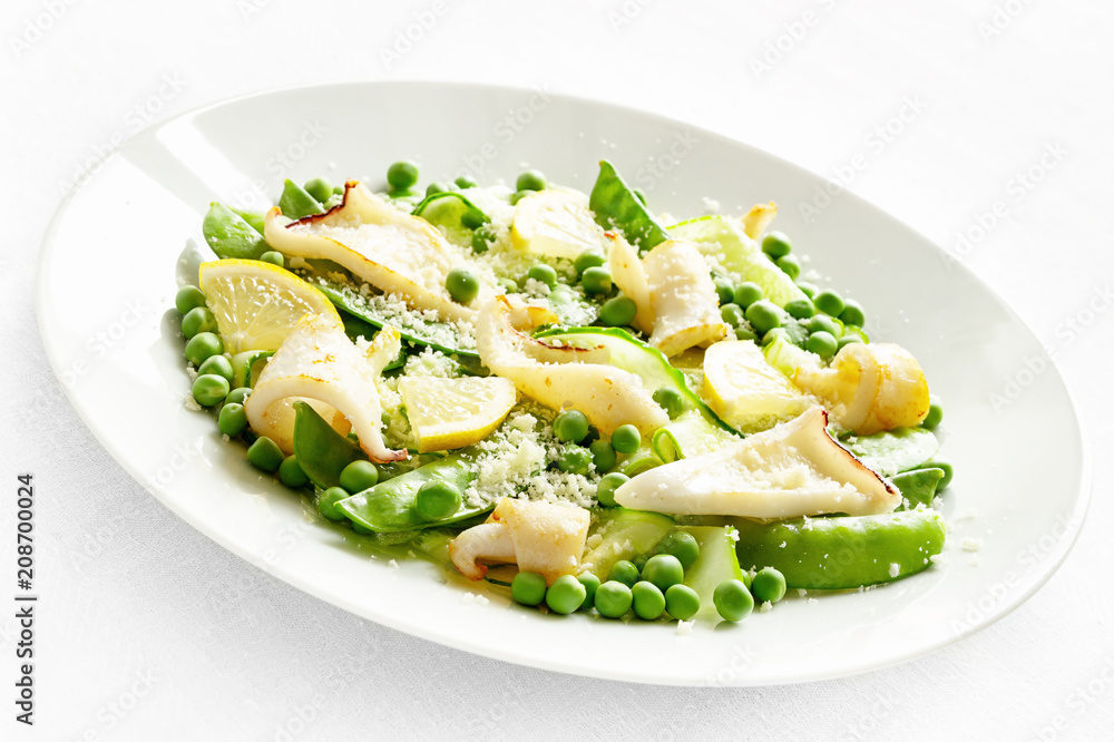 fried calamari salad with pea, pea pods,lemon, cucumber decorated with grated cheese and dressed with oil and vinegar