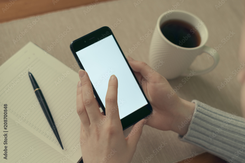 Cup of coffee on a wooden table, smartphone and notebook and pen.