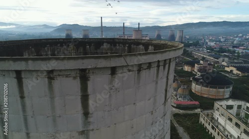 Drone shot flying past old cooling tower revealing huge abandoned industrial complex in Albania, Southeastern Europe