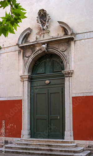 Old Church door in Venice. Italy. The door is decorated with bas-reliefs and decorative elements. Above the door is a skull sculpture
