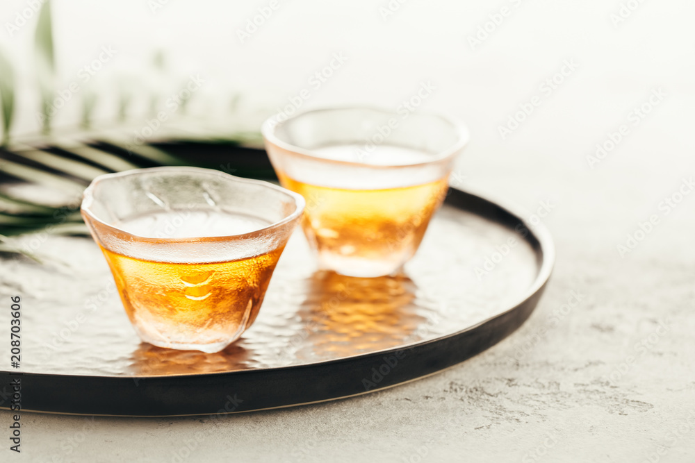 Two glass cups of freshly brewed tea on a tray. Selective focus. Two glass cups of freshly brewed tea on a tray. Selective focus.