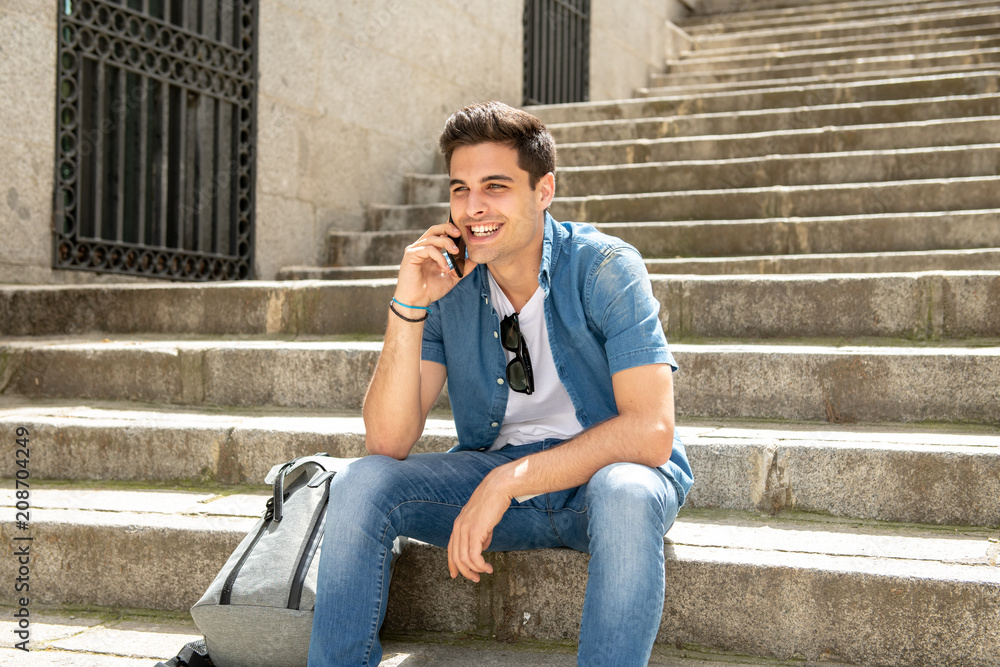 Handsome modern happy young man talking on his smart phone outside in the city. Handsome modern happy young man talking on his smart phone outside in the city.