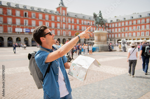good looking young man traveler holding up a map in madrid