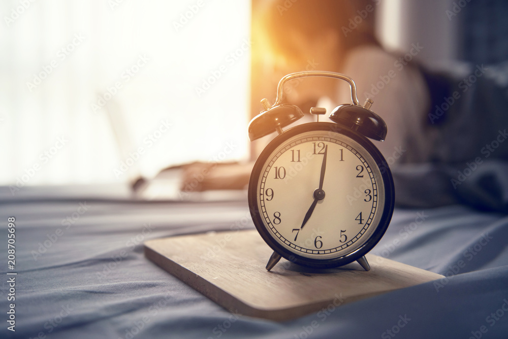 Closeup alarm clock, Business woman wake up and working with laptop  computer on bed in morning, start new project concept Photos | Adobe Stock
