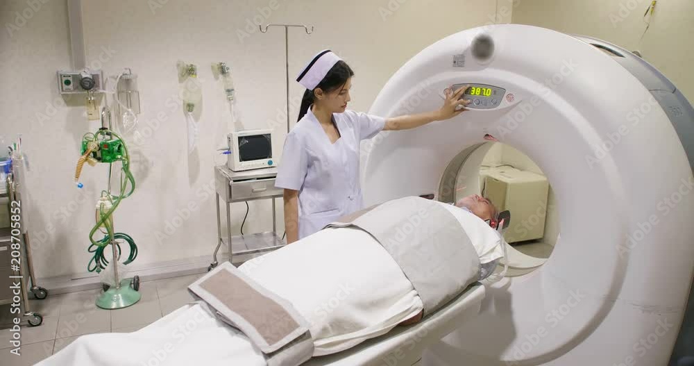 Middle aged man lying on the CT scanner during machine imaging his body, lights up infrared rays and male patient passes through the circle. Middle aged man lying on the CT scanner during machine imaging his body, lights up infrared rays and male patient passes through the circle.