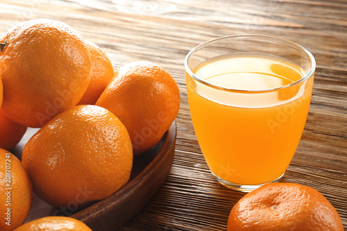 Obraz na płótnie Ripe tangerines and glass of juice on table, closeup