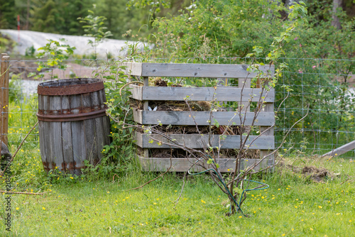 old wooden barrel standig beside a garden compost