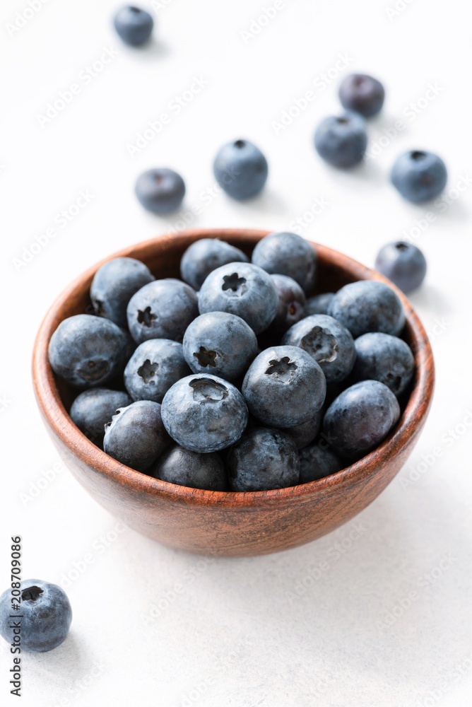 Blueberries in wooden bowl on white background. Closeup view, selective focus Blueberries in wooden bowl on white background. Closeup view, selective focus
