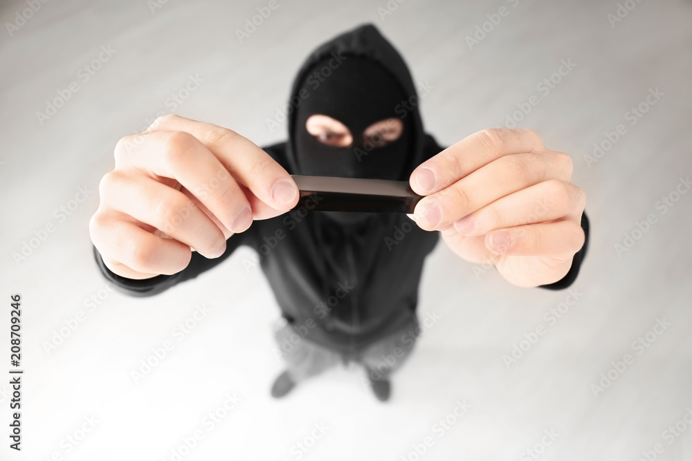 Thief putting sticky tape onto camera of alarm system, indoors Thief putting sticky tape onto camera of alarm system, indoors