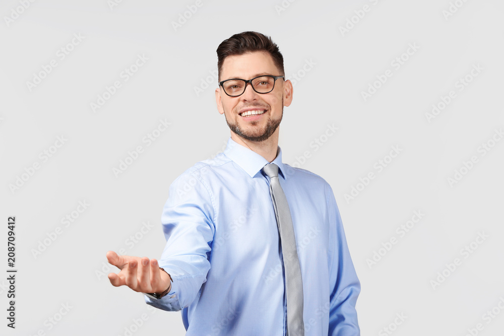 Young businessman holding something on gray background Young businessman holding something on gray background