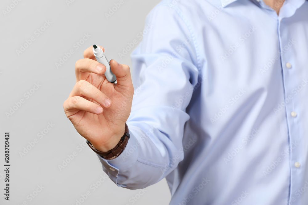 Young businessman writing on virtual screen against gray background Young businessman writing on virtual screen against gray background