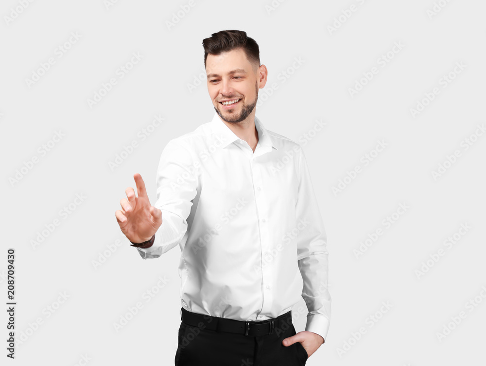 Young businessman using virtual screen on gray background Young businessman using virtual screen on gray background