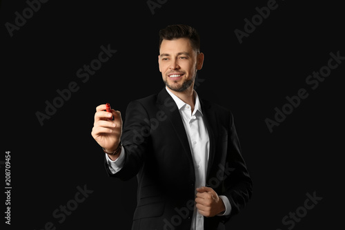 Young businessman writing on virtual screen against black background