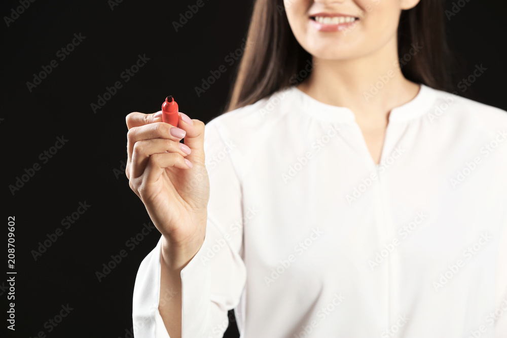 Young businesswoman writing on virtual screen against black background Young businesswoman writing on virtual screen against black background