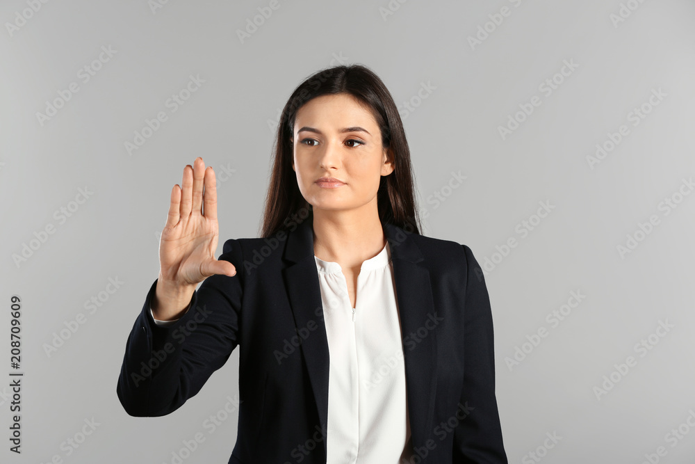 Young businesswoman using virtual screen on gray background Young businesswoman using virtual screen on gray background