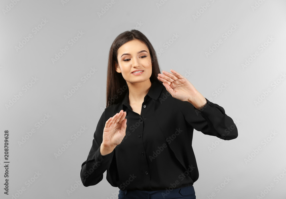 Young businesswoman using virtual screen on gray background Young businesswoman using virtual screen on gray background