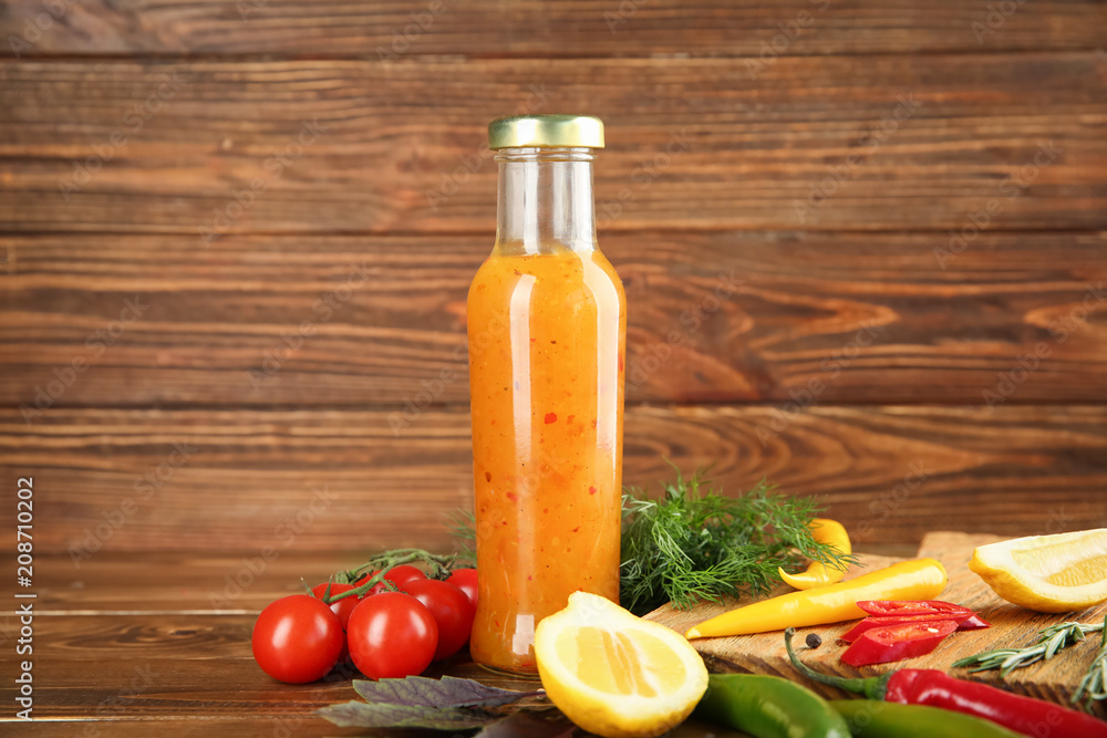 Bottle with tasty sauce and ingredients on wooden background Bottle with tasty sauce and ingredients on wooden background