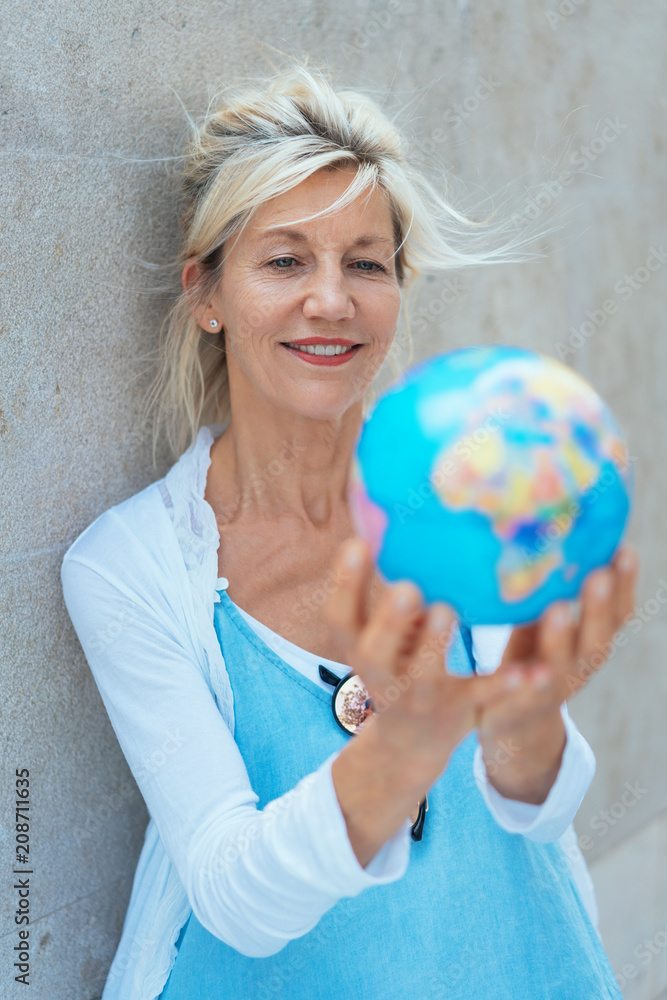 Fototapeta premium Middle-aged blond woman holding a world globe