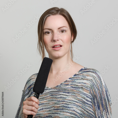 Junge Frau mit einem Mikrofon in der Hand und fragendem Blick photo