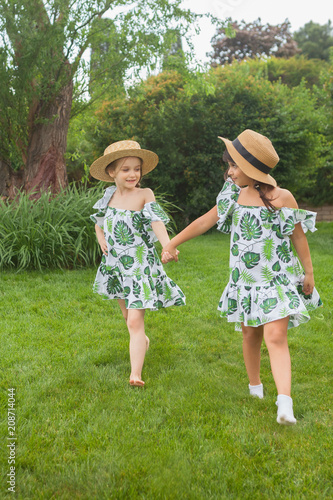 Portrait of smiling beautiful girls with hats against green grass at summer park.