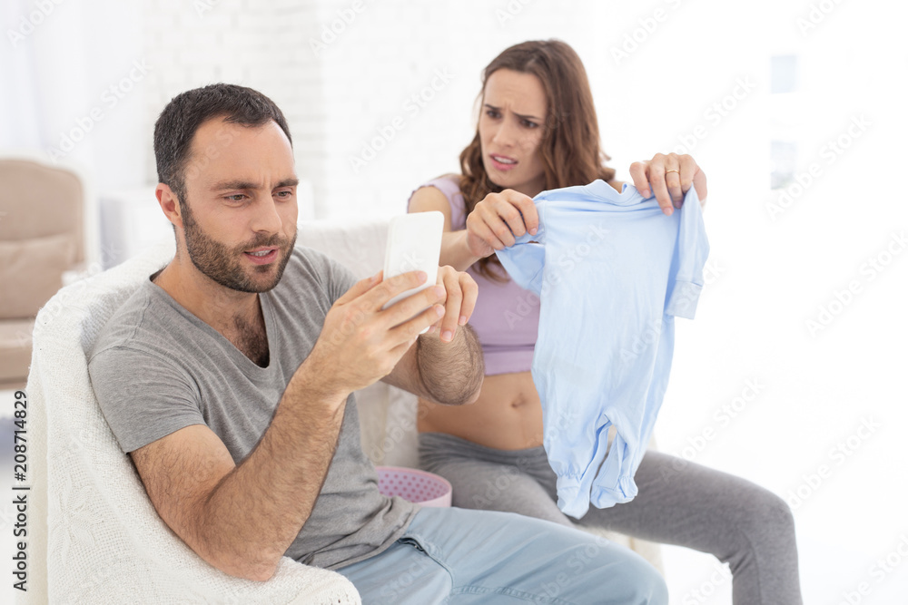 Total ignorance. Merry man neglecting pregnant woman and looking at phone screen Total ignorance. Merry man neglecting pregnant woman and looking at phone screen