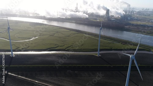 Aerial view of solar park with active wind turbines in background showing some heavy industry and nuclear power plant showing the exhaust fumes emerging from the cooling towers 4k high resolution photo